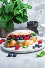 Croissant with raspberries, blueberries and cream cheese on a white plate