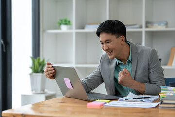 confident young businessman Happy smart gesture excited with laptop computer and raised arms to celebrate happy financial business success startup business ideas.