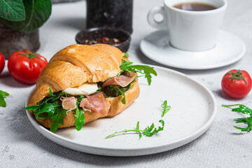 Croissant with jamon, mozzarella and arugula on a plate