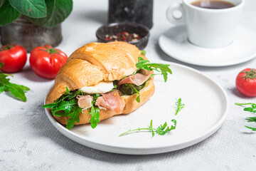 Croissant with jamon, mozzarella and arugula on a plate