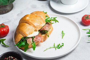 Croissant with jamon, mozzarella and arugula on a plate