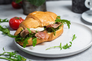 Croissant with jamon, mozzarella and arugula on a plate
