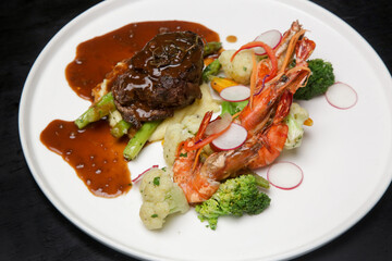 Steak and shrimps with mashed potatoes and vegetables served on the restaurant table. Exquisite dish, creative restaurant meal concept