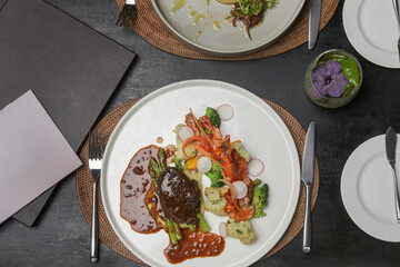 Steak and shrimps with mashed potatoes and vegetables served on the restaurant table. Exquisite dish, creative restaurant meal concept