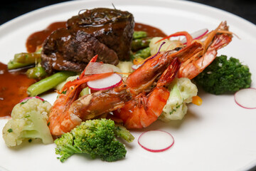 Steak and shrimps with mashed potatoes and vegetables served on the restaurant table. Exquisite dish, creative restaurant meal concept