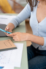 Young woman sitting at her desk at home using her cell phone.