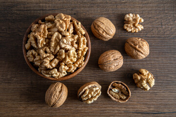 Peeled walnuts and whole walnuts in wooden bowl,top view
