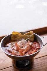 Seafood Tom Yum, hot and sour Thai soup with squid, shrimp served in hot pot