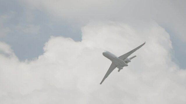 Large white private business Jet during flight under blue sky with clouds
