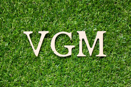 Wood alphabet letter in word VGM (abbreviation of verified gross mass) on artificial green grass background