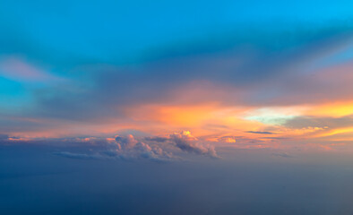 Bright orange sunset between ominous clouds, fading daylight seen from the air. Aerial image of brooding storm