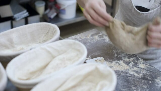 Female hands knead a loaf of bread in the form of dough and put it in a baking dish
