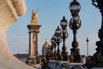 Fototapeta na wymiar Farolas en el puente Alexandre III con el Palacio de los Inválidos de fondo, París