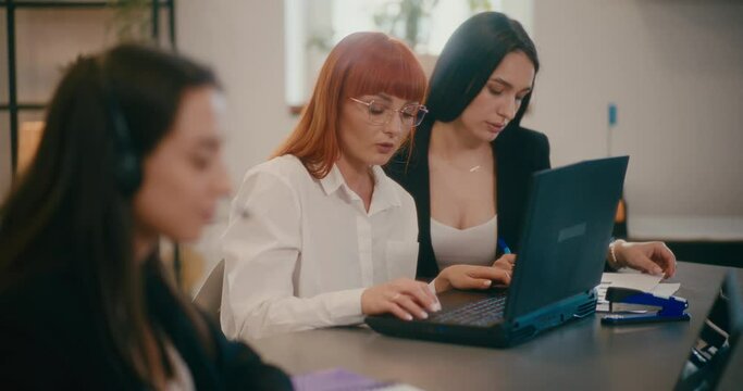 Businesswomen working on laptop at desk in office.