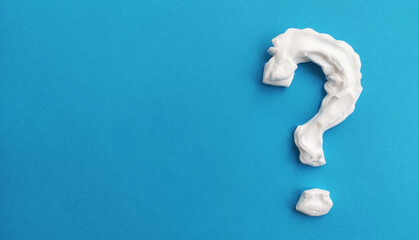 Question mark made of cream or shaving foam on blue background
