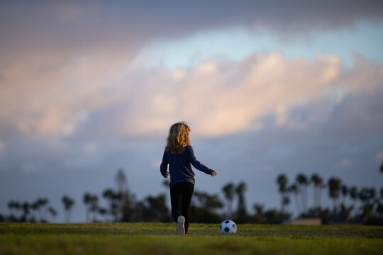 Kid playing soccer, happy child enjoying sports football game, kids activities, little soccer player back view.
