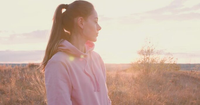 young beautiful woman looking around, enjoying beauty of landscape Slow motion, sportswoman takes break after workout in countryside Relaxation, lady in sportswear going to train on fresh air outdoors