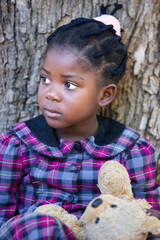 african girl with braids playing with an old teddy