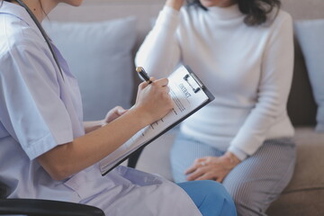 Asian doctor woman visited patient woman to diagnosis and check up health at home or private hospital. Female patient explain health problem and symptoms to doctor .Health care premium service at home