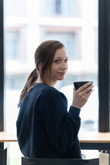 Attractive young office worker holding a  binder as she looks at the camera with a sweet friendly smile