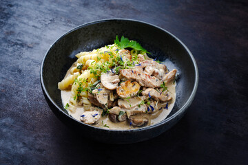 Traditionelles Zürcher Geschnetzeltes vom Kalb mit Pilzen und Nudeln in Rahmsauce serviert als Nahaufnahme in einem Nordic Design Teller