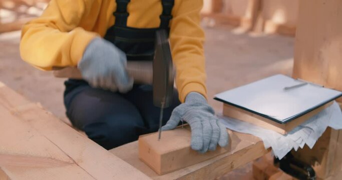 young female carpenter in uniform and gloves learning to hammer nails, Slow motion Woman is using hammers to nail wood.