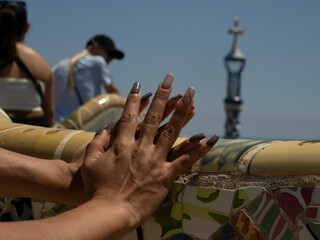 woman hands on ceramic tiles of barcelona park guell spain gaudi masterpiece