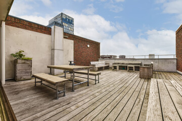 an outdoor deck with picnic tables and benches in the fore - image is taken from outside, looking...