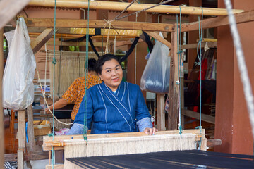 Asian female weavers weaving traditional patterns with hand weaving machines.in the concept of...