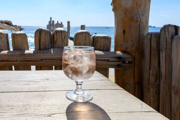 Summer time in Provence, glass of rose wine with ice cubes on bar terrace Pampelonne sandy beach...