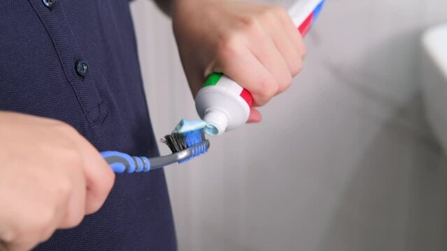 kids hands squeeze toothpaste onto toothbrush in bathroom at home, Health care, dental hygiene.