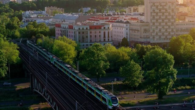 Aerial city view, drone shot of trains passing by the bridge over the Vistula river in Warszawa (Warsaw, Poland). Train heading into the city center of Warsaw in Poland. 