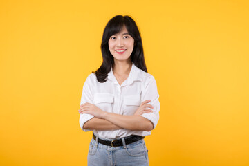 Young Businesswoman. Portrait asian woman happy smiling, posing confident, cross arms on chest, standing against yellow studio background. Smart young entrepreneur advertising products and services.