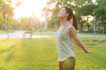 Female jogger. Fit young Asian woman with green sportswear breathing fresh air in park before...