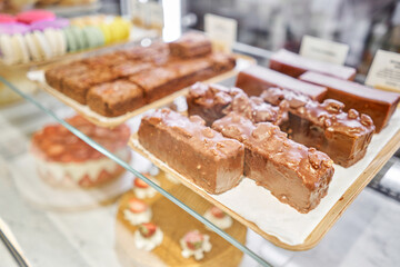 A variety of cakes covered with chocolate and decorated with pistachio mousse. A showcase in a pastry shop with delicious desserts with fresh berries and cream. Delicious pastries in the coffee shop.