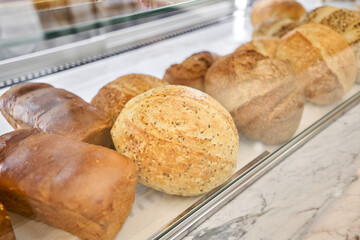 Different kinds of bread on the counter in the bakery shop. Fresh bread counter. Modern bakery with different kinds of bread, cakes and buns 