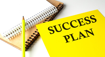SUCCESS PLAN text written on a yellow paper with notebook