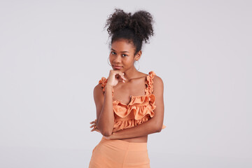 With a bold and beautiful presence, a black girl poses gracefully in an orange shirt, showcasing...