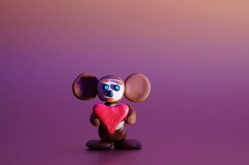 A toy cheburashka with a heart on a colored background. Children's toys.