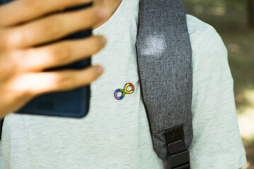 Teenage boy with autism infinity rainbow symbol sign using smartphone outdoors. World autism...
