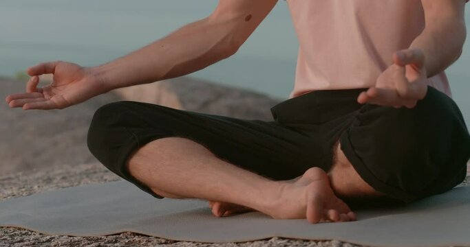 cropped picture shoot male sitting in lotus position man on rocks outdoors meditating sitting in lotus position man without face zen catching sitting in lotus position man in outdoor Enlightened guy