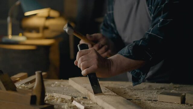 Shavings, Manual worker Concentrated Holds a chisel and a hammer works with wood In the workshop Close-up Engineering worker Works with solid wood at the desktop In the woodworking shop, hobby

