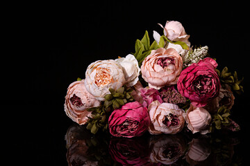Ramo de peonías en diferentes tonos de rosa sobre fondo negro.