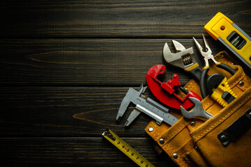 Professional tools for the master plumber in a suede bag on a black vintage table. Free space for...