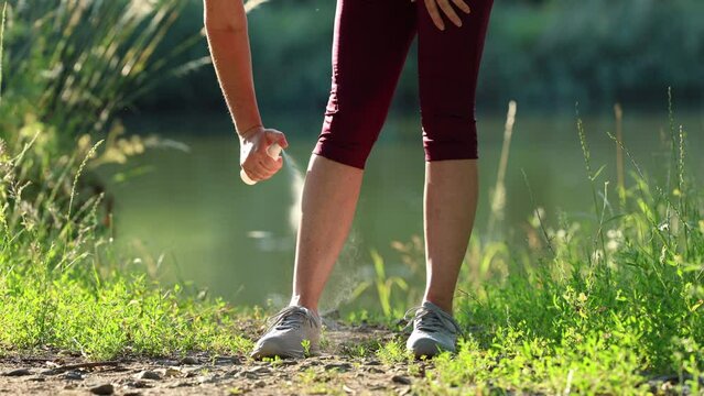 Woman applying insect repellent against mosquito and tick on her leg before running outdoors