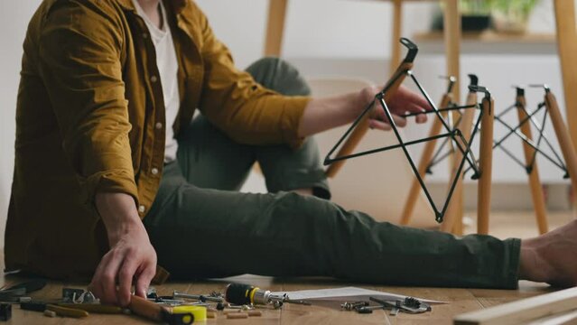 Furniture expert, Engineer Studying instructions for furniture assembly while assembling a chair In private house, Close-up of a man Assembling new furniture in a new house In his apartment, carpenter