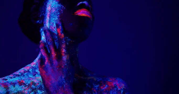 beautiful african sensual woman in neon UF light looking aside. attractive young model girl with fluorescent creative psychedelic make-up, body-art Beauty concept