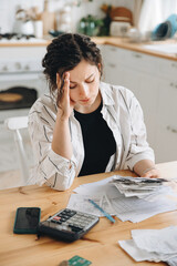 Stressed caucasian woman trying to deal with financial documents, having problem to find money to...