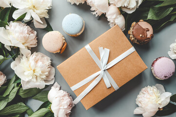 Fototapeta na wymiar Gift box with bow, white peonies and sweet macaroons, holiday concept