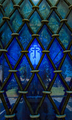Christian cross seen through the barred windows of a church.